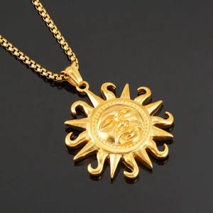 Macro shot of gold sun face pendant with detailed embossing on black reflective background
