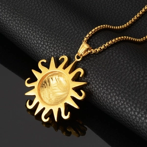 Close-up of golden sun pendant with wavy rays on black leather and mirror surface