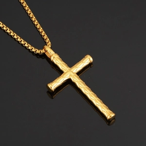 Polished gold hiphop cross necklace with textured cylinder pendant on black background