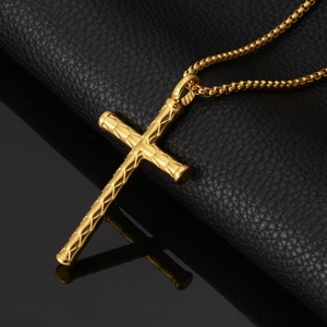 Close-up of golden stainless steel cross pendant with bamboo texture on black leather