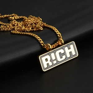 Détail du pendentif doré R!CH avec une chaîne à maillons cubains en acier titane