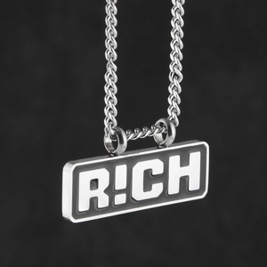 Gros plan d'un pendentif RICH en acier inoxydable argenté de style hip-hop