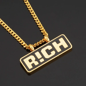 Détail rapproché d'une chaîne cubaine dorée et pendentif à lettres R!CH noires