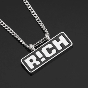 Détail du collier hip-hop R!CH en argent avec chaîne gourmette sur miroir noir poli