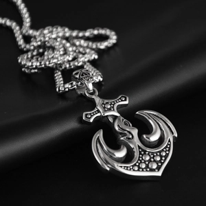 Close-up of vintage silver anchor pendant with skull detail on black leather background