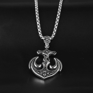 Macro detail of gothic skull and anchor pendant on a silver box chain necklace