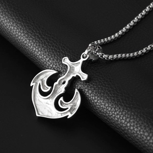 Detailed close-up of retro silver anchor pendant with box chain on black leather background