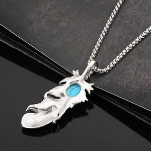 Détail macro du pendentif plume en argent avec pierre turquoise et chaîne en acier