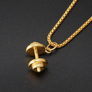 Macro shot of gold dumbbell pendant necklace on a textured black background