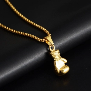 Macro side view of a 3D boxing glove pendant in gold finish with beaded necklace chain