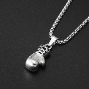 Detail of silver boxing glove pendant with box chain on a dark textured background