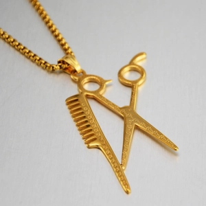 Dettaglio della collana con ciondolo a forbice e pettine dorati su sfondo metallico