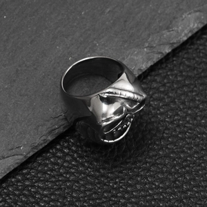 Gros plan d'une bague tête de mort argentée avec masque mécanique sur fond de pierre noire
