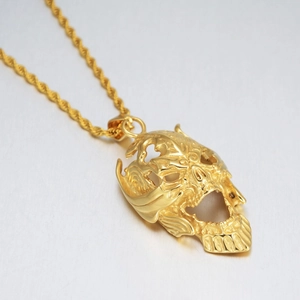 Détail d'un pendentif crâne évidé doré avec chaîne de corde de style punk