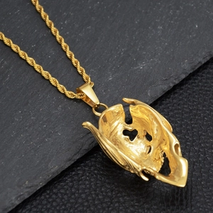 Détail d'un collier chaîne torsadée dorée avec pendentif abstrait sur roche noire
