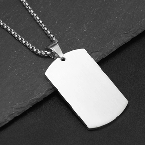 Détail du pendentif plaque en acier inoxydable brossé sur une pierre noire texturée