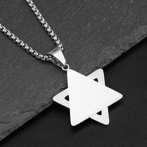Vue macro d'un pendentif étoile à double triangle argenté sur fond en ardoise noire