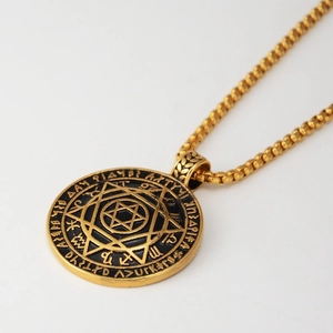 Makroaufnahme des goldenen Hexagramm-Anhängers mit mystischen Runen und Kugelkette