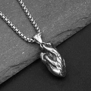 Pendentif cœur anatomique punk détaillé avec chaîne box sur fond de pierre texturée