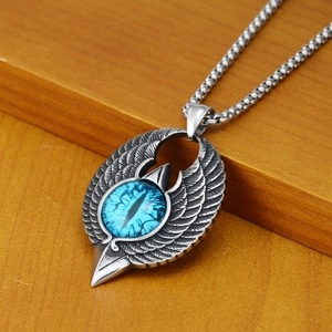 Macro shot of hip hop eagle wing necklace with blue dragon eye stone on wood