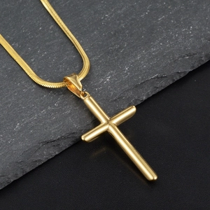Détail macro d'un pendentif croix dorée polie avec une chaîne serpent élégante et chic
