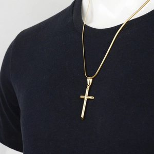 Gros plan d'un collier avec pendentif croix tubulaire en or poli sur un t-shirt noir