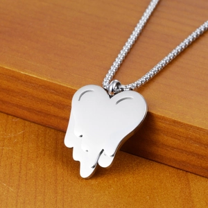 Dettaglio macro del ciondolo a cuore fuso argento con catena su superficie in legno