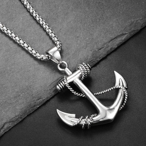 Macro shot of a silver steel anchor pendant with rope details on textured rock