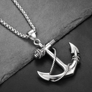 Macro detail of silver anchor pendant with rope texture on a rugged stone background