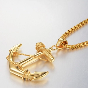 Macro detail of golden anchor pendant with rope texture and stainless steel box chain