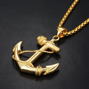 Macro shot of gold anchor pendant with rope detail on black leather background