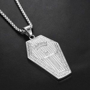 Macro view of silver coffin pendant necklace with pavé diamonds and crown cross engraving
