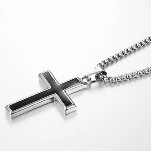 Détail d'un pendentif croix en acier poli avec centre en émail noir sur une chaîne à billes