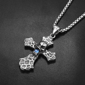 Détail d'un pendentif croix gothique avec crâne et pierre bleue sur cuir noir