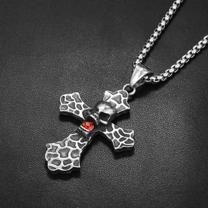 Gros plan d'un pendentif croix gothique en lave avec crâne et pierre de zircon rouge