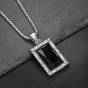 Gros plan d'un pendentif onyx noir rectangulaire avec motifs en relief et chaîne box