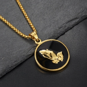Detail of gold-plated box chain with black enamel round pendant featuring praying hands