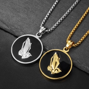Detailed macro view of gold and silver prayer hand embossed pendants on black round discs
