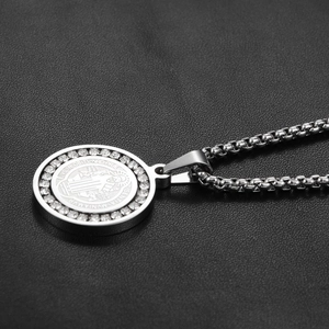 Detailed close-up of Saint Benedict medallion necklace with white rhinestones on black leather