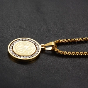 Macro shot of gold Saint Benedict medal pendant with zircon inlay on black leather