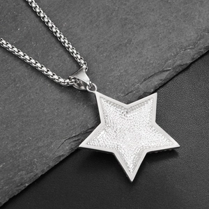 Detalle macro del colgante de estrella plateada con acabado pavé y cadena de caja gruesa