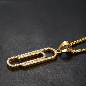 Gros plan d'un pendentif trombone doré serti de zircons blancs sur chaîne box maille