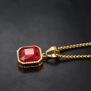 Macro di un ciondolo con pietra rossa taglio smeraldo e alone di zirconi su catena oro