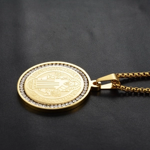 Macro side view of golden Saint Benedict religious pendant with zircon border inlay
