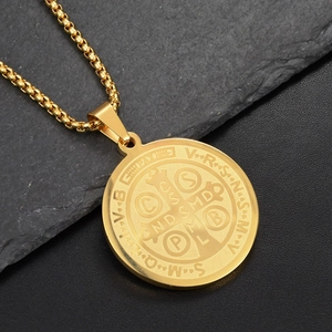 Detail of gold Saint Benedict medal pendant featuring religious cross and Latin engravings