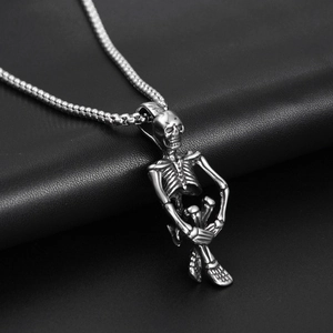 Macro detail of gothic sitting skeleton pendant made of polished silver titanium steel