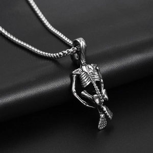 Detailed macro view of a vintage gothic skeleton pendant on a black leather surface