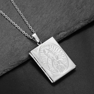 Macro shot of silver book locket with Virgin Mary engraving on rock and leather