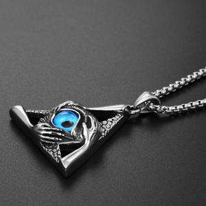 Macro detail of gothic triangle pendant with blue eye and skull hands on round box chain