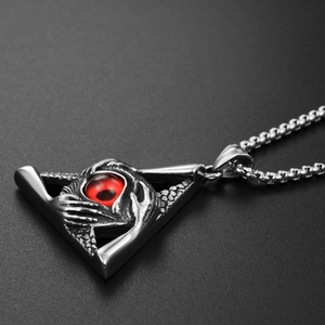 Macro shot of gothic triangle pendant featuring red all-seeing eye and hand relief